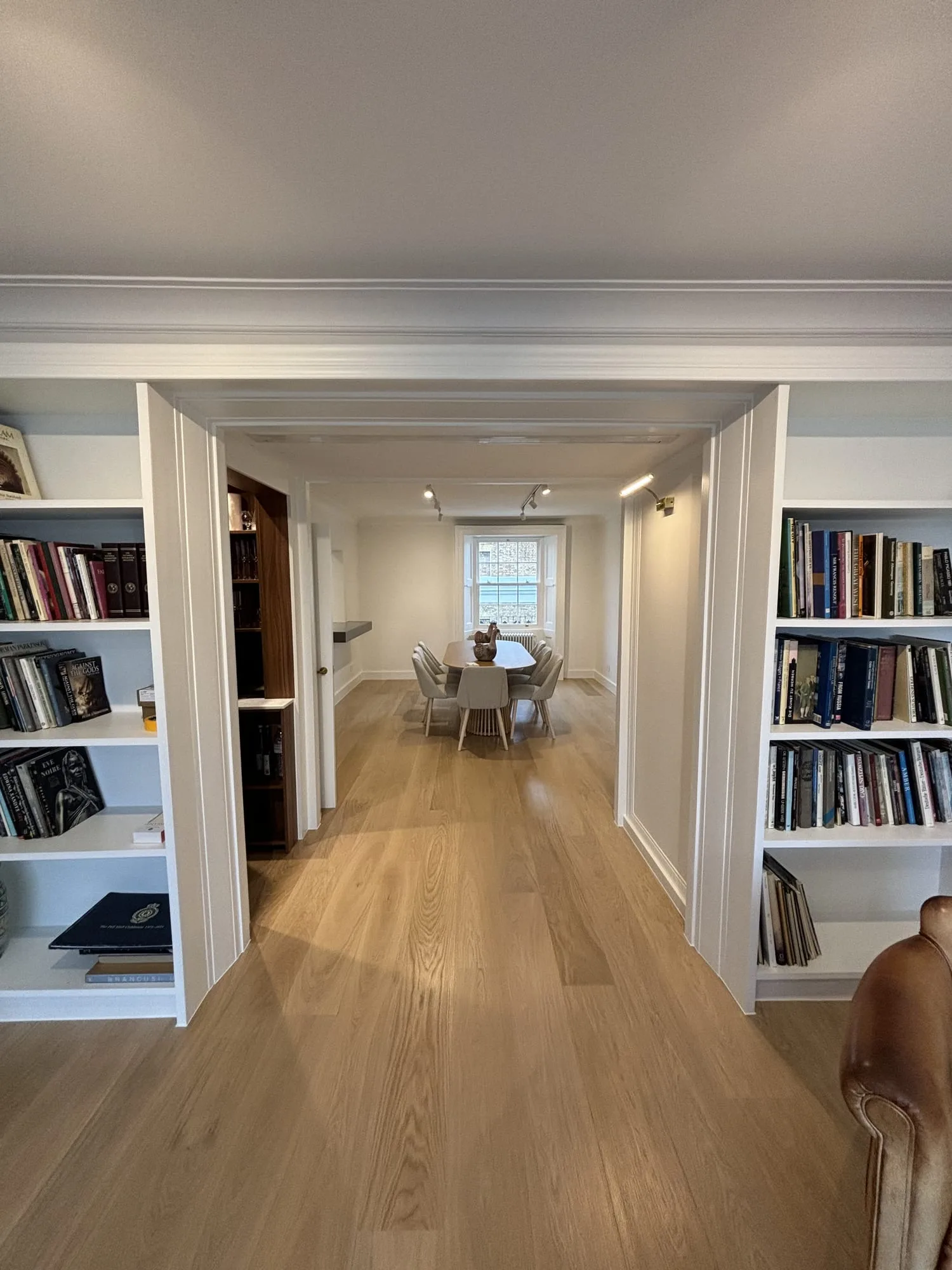 Belgravia: hallway lined with built-in bookshelves leading to the dining room