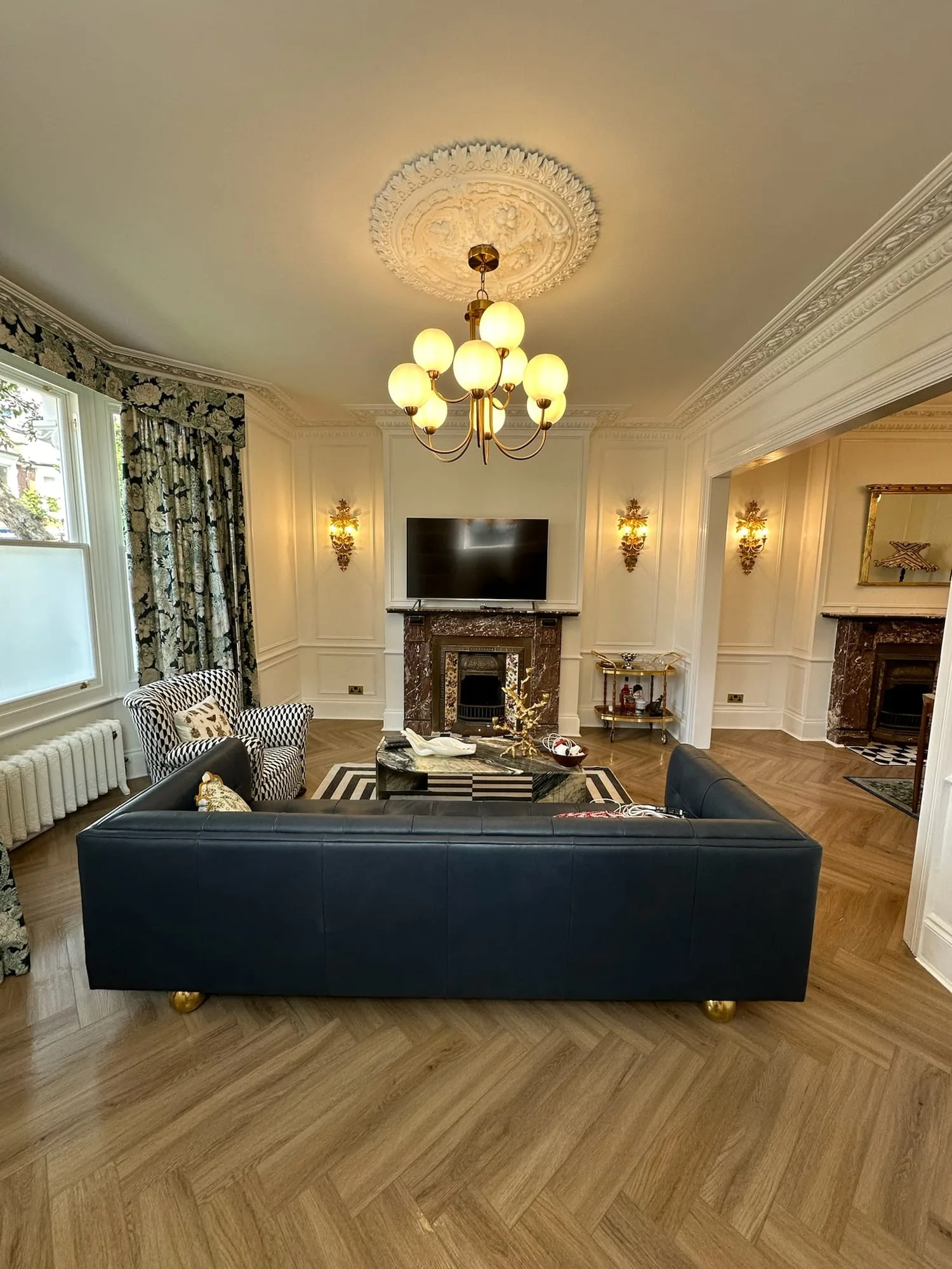 Earls Court I: drawing room with a marble fireplace, chandelier and herringbone parquet