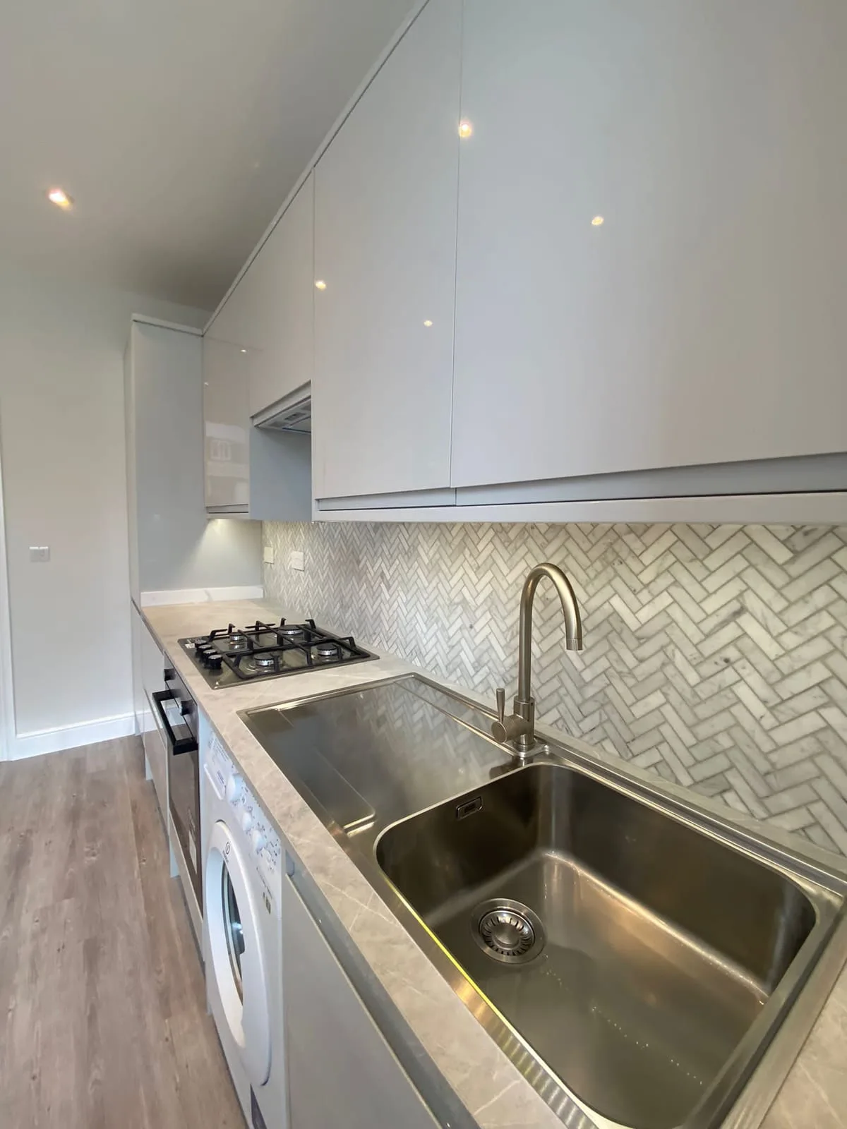 Kitchen detail: a herringbone marble mosaic splashback above a stone worktop